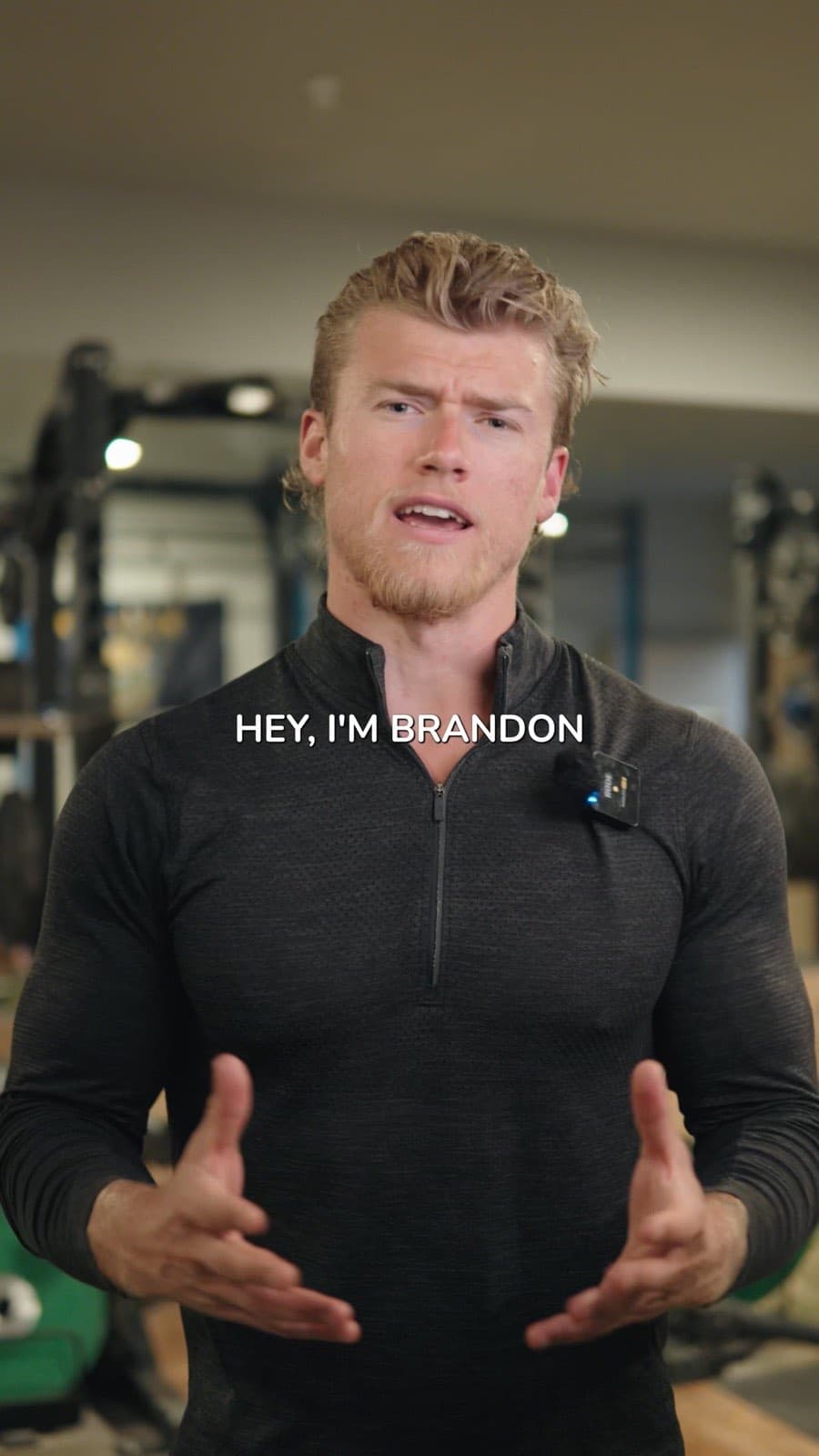 Brandon Clark in a grey quarter-zip talking to camera in a gym, on-screen caption reading Hey, I'm Brandon