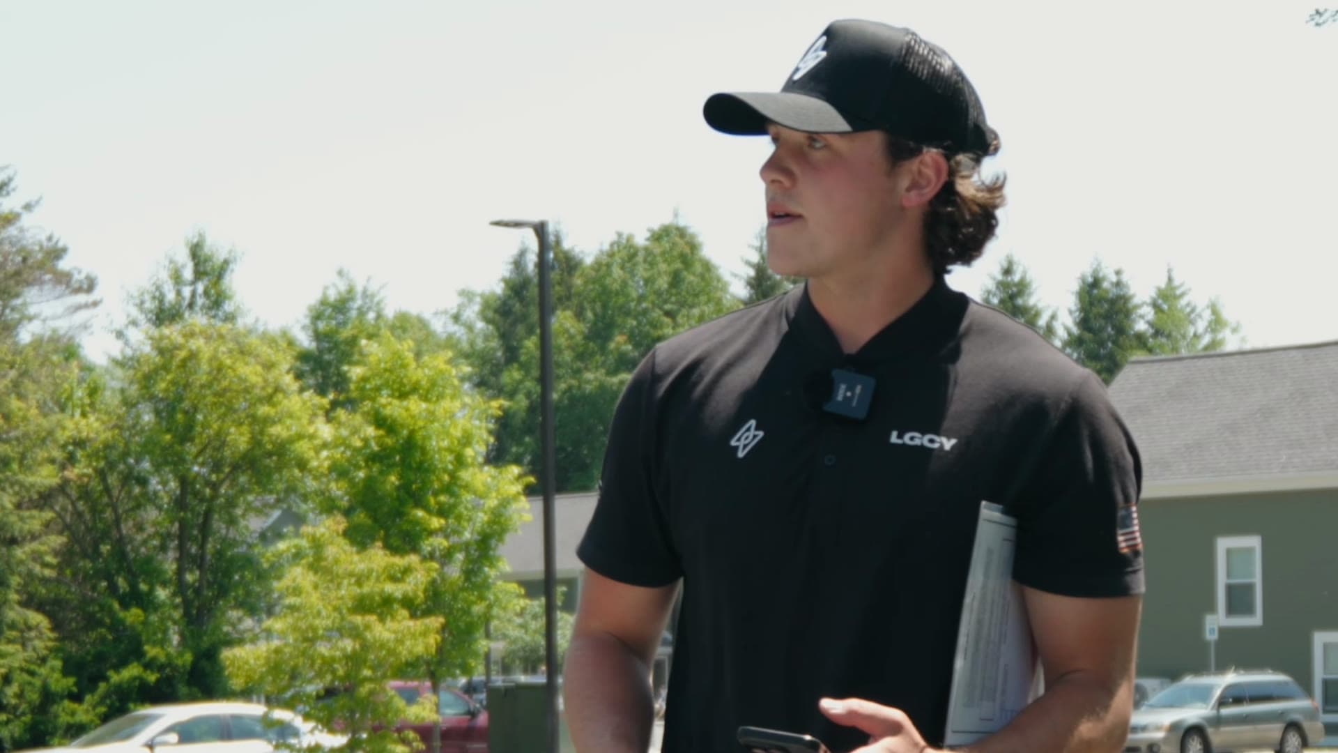 Flex PWR rep in a black cap and polo standing on a residential street with his phone