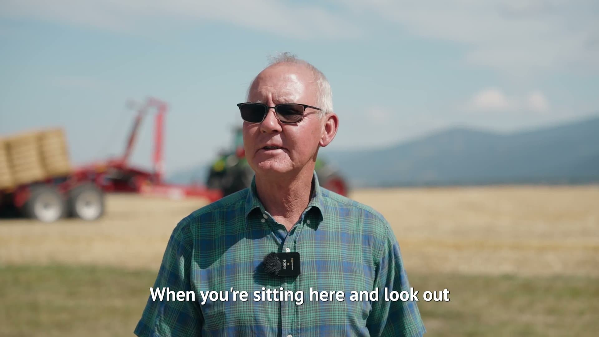 Gallatin County farmer in sunglasses and a plaid shirt talking beside a hay field, subtitle reading When you're sitting here and look out