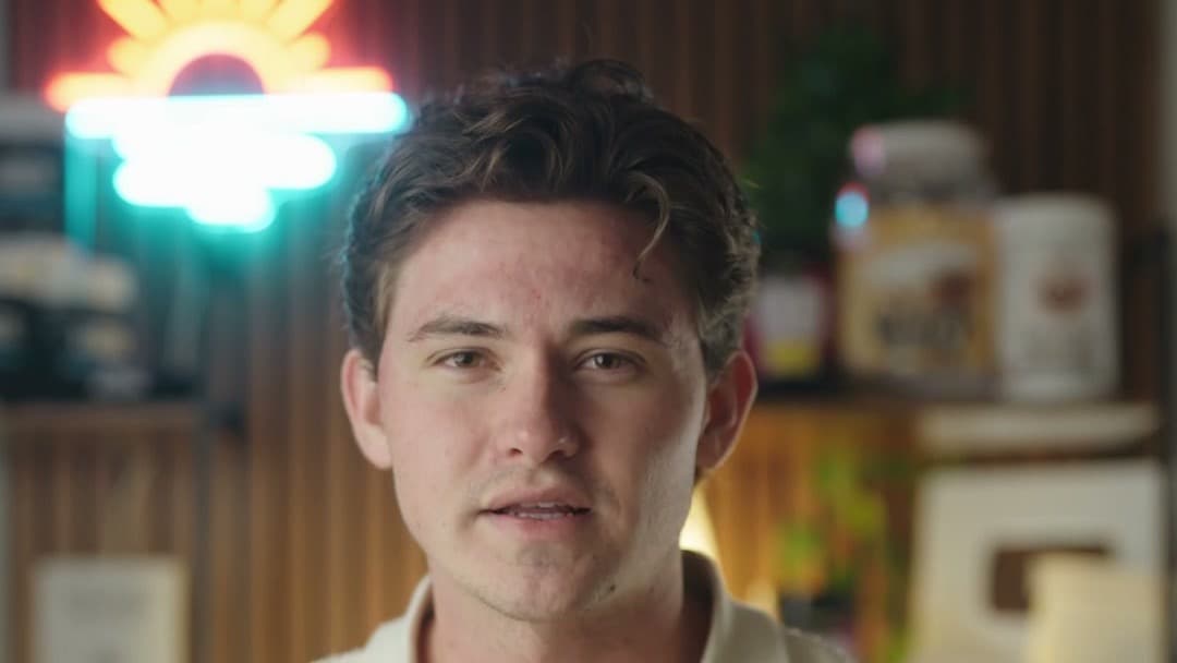 OB Health client talking to camera in a kitchen under a neon sunrise sign