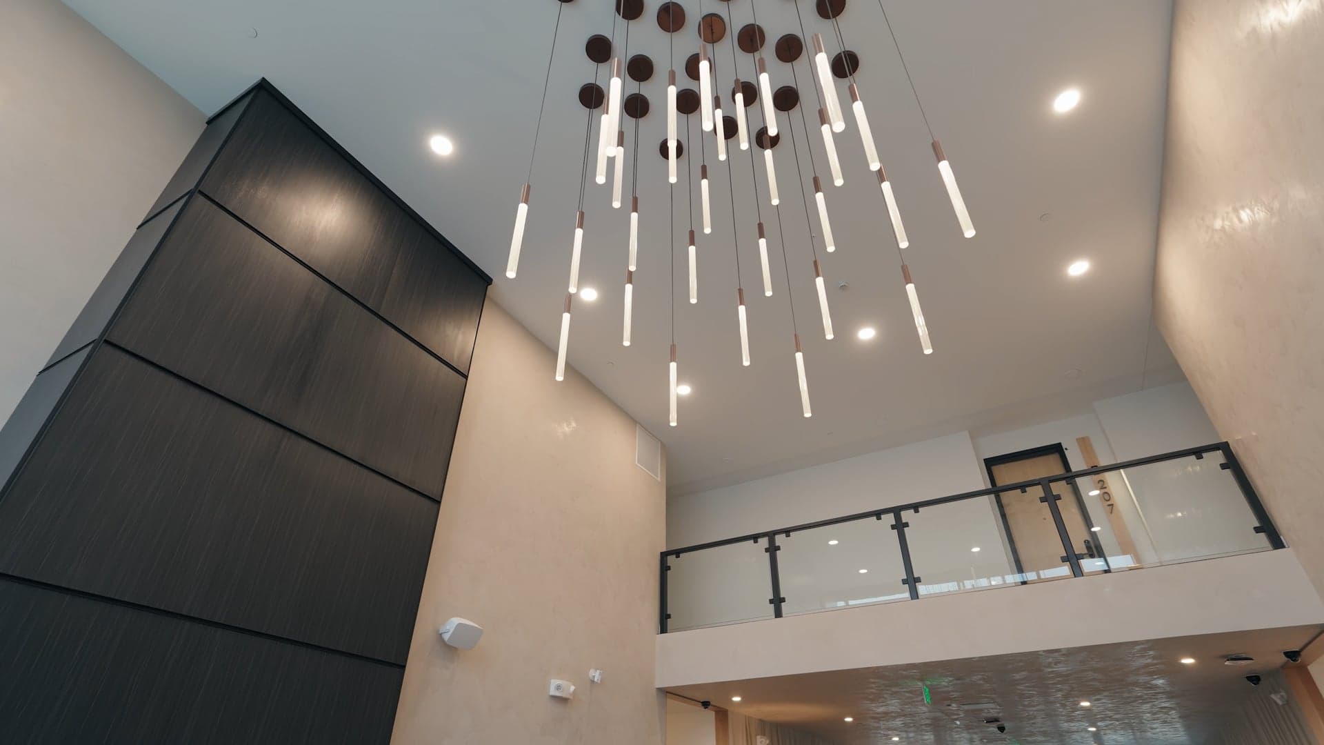 Two-storey lobby at The Kestrel with a hanging cluster of tube pendant lights over the stair